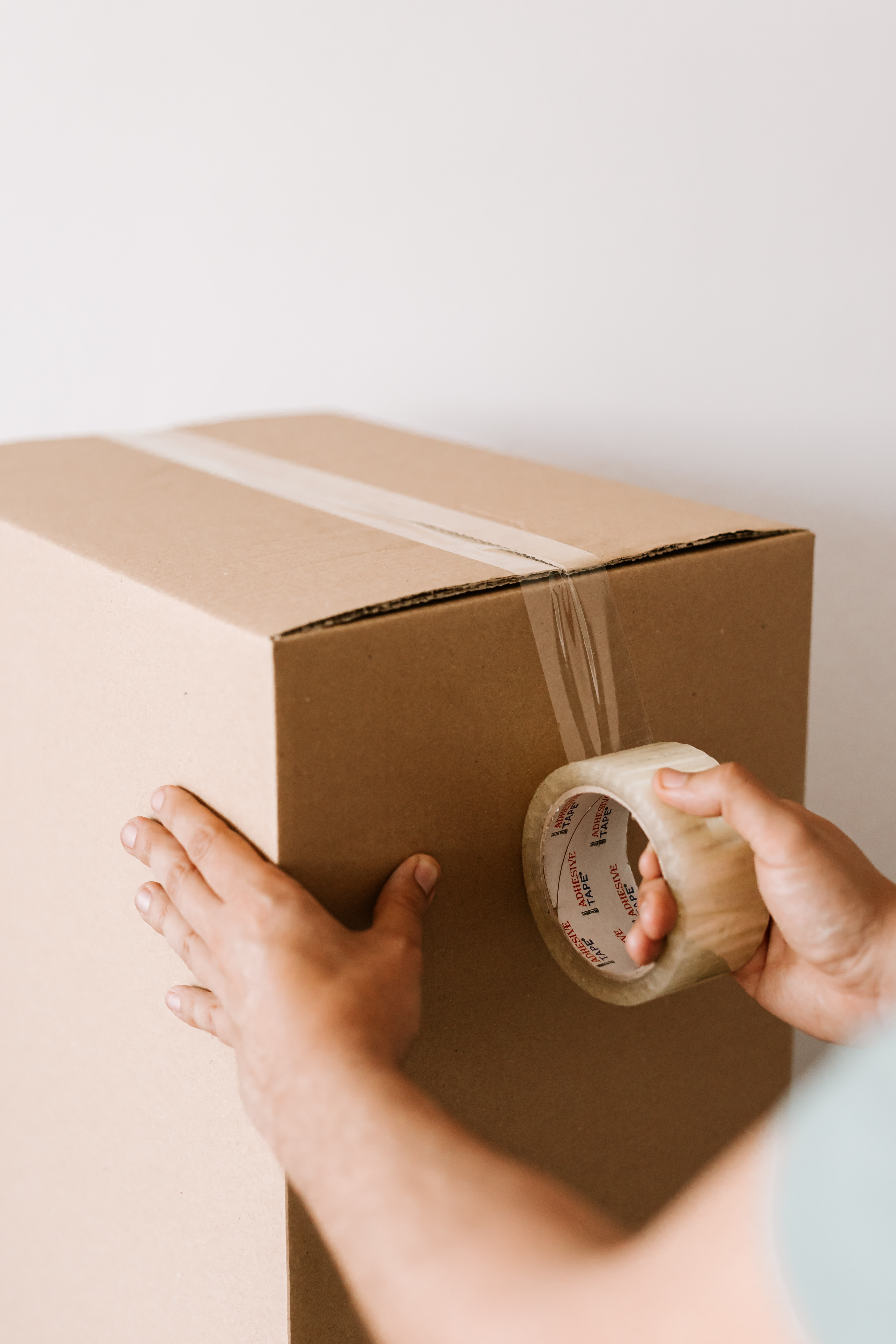 A hand tapes up a box ready for moving